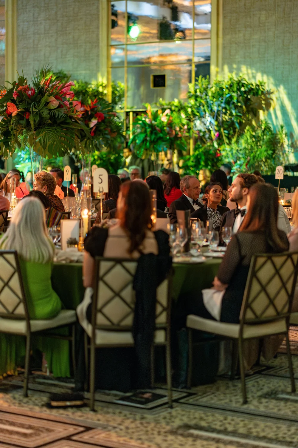 Guests in conversation at dinner tables with tall tropical floral centre pieces during The Hope Gala
