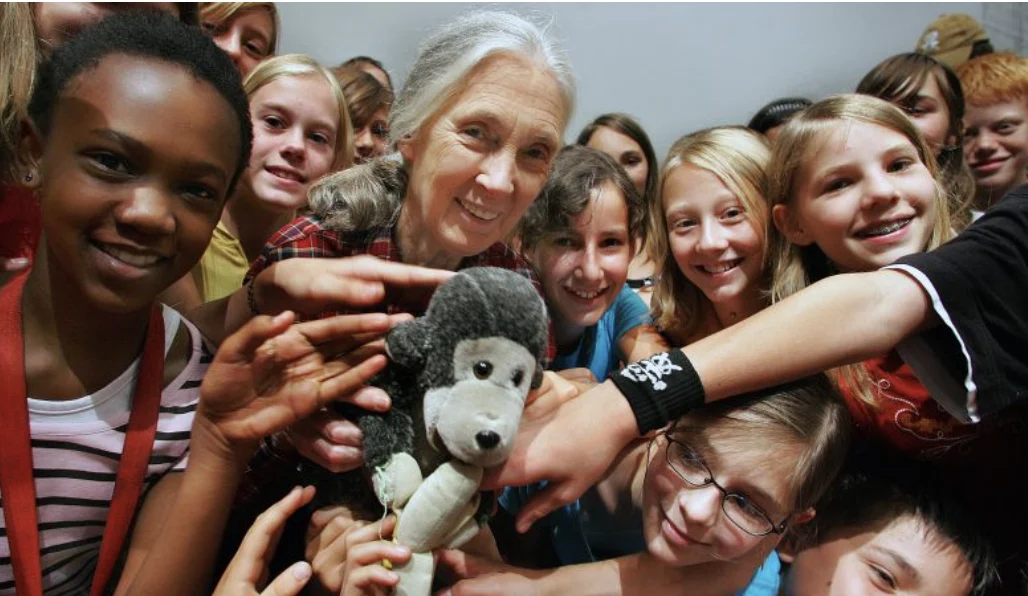 Dr Jane Goodall surrounded by smiling children from Roots & Shoots