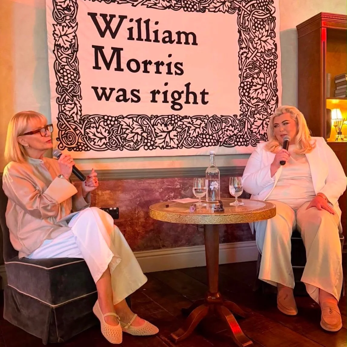 Two guests in conversation beneath a William Morris was right banner at a Prime Time Reset live event
