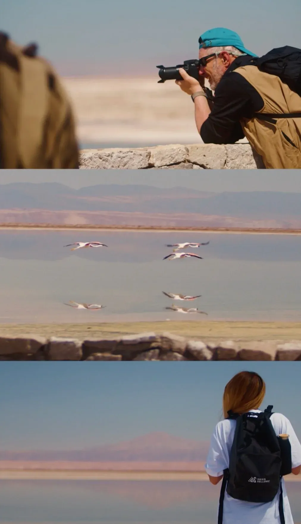 A man in a blue cap and sunglasses photographing flamingos flying over water, with a woman wearing a backpack watching from behind