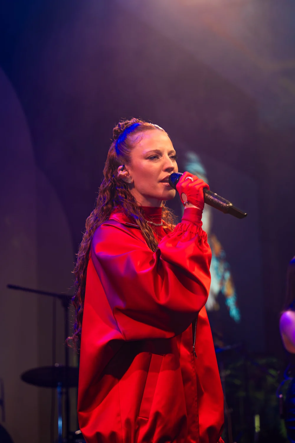 A singer in a red jacket performing on the stage of The Hope Gala